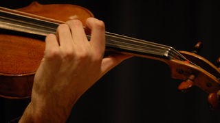 Eine Hand, mit der Geige gespielt wird.