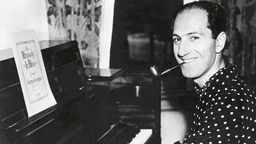 George Gershwin mit Pfeife am Klavier und Rhapsody In Blue