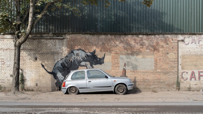 Ein neues Kunstwerk des Streetart-Künstlers Banksy zeigt ein Nashorn an einer Wand.