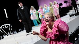 Probenaufnahme aus "Der Zwerg" in der Oper Köln, lachende Frau in pinkem Kleid.