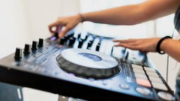 Hände einer DJane am DJ-Pult, um Sounds zu mixen.