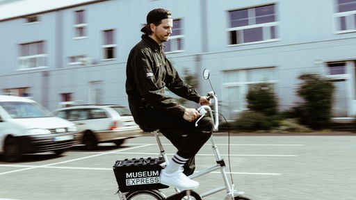 Sebastian Jung, Gründer von "Museum Express", fährt Fahrrad.