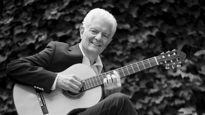 Schwarz-weiß Foto von Peter Horton mit Gitarre in der Hand.