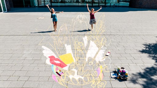 Lydia (l) und Vanessa Hitzfeld malen ein riesiges Taylor-Swift-Bild vor dem Hans-Sachs-Haus in der Innenstadt von Gelsenkirchen.