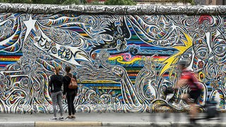 Touristen laufen in Berlin an der "East Side Gallery", dem größtten noch verbliebenem Reststück derBerliner Mauer entlang