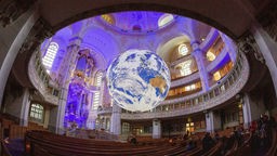 Im Hauptraum der Dresdner Frauenkirche schwebt eine sieben Meter grosse blau leuchtende Erdkugel.