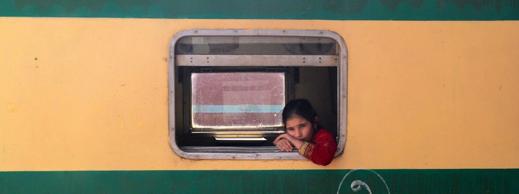 Ein Mädchen schaut aus einem Zugfenster auf den Bahnhof Peschawar.