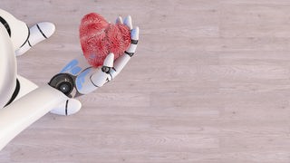 Roboter hält ein Herz in der Hand.