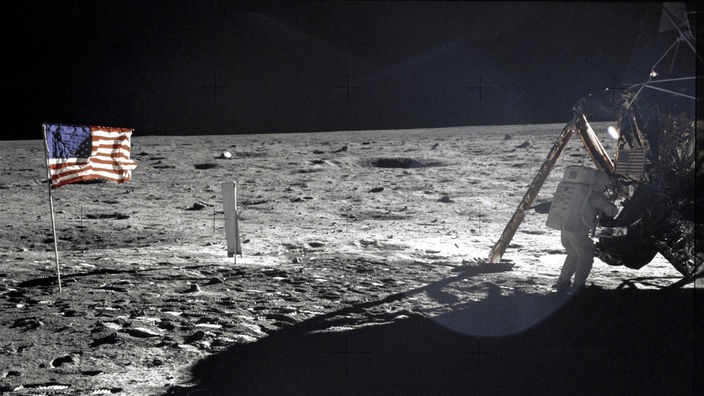 Foto der ersten Mondlandung von Apollo 11 mit einer gehissten amerikanischen Flagge und einem Besatzungsmitglied