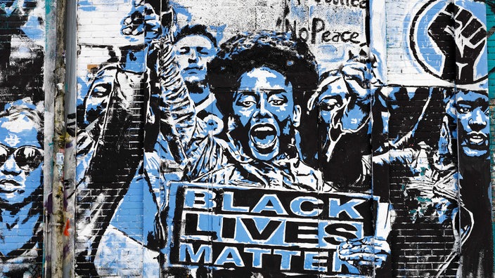 Ein Graffiti, welches eine Schwarze Frau bei einem Black-Lives-Matter-Protest abbildet.