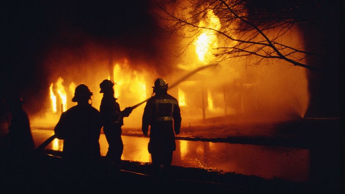 Feuerwehrkräfte löschen ein brennendes Haus.