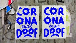 Zwei Plakate mit der Aufschrift: "Corona bleibt doof" und einem traurigen Smiley.