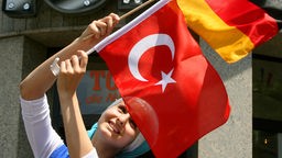 Frau schwenkt eine deutsche und eine türkischen Flagge.