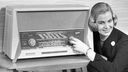 Eine Frau sitzt neben einem Radiogerät der Firma Graetz; lächelnd und am Knopf drehend.