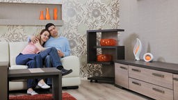 Junges Paar sitzt auf einer Couch, modernes Wohnzimmer.