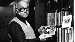 Schwarz-weiß: Ottfried Preußler steht in den 70ern vor einem Bücherregal mit seinen eigenen Büchern.