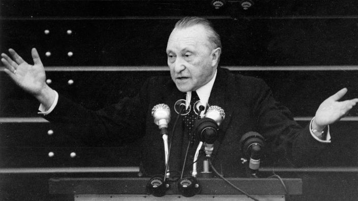Alt-Bundeskanzler Konrad Adenauer steht am Pult und hält Rede.
