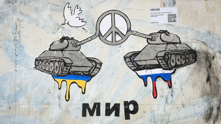 Graffiti von der Künstlerin Laika: Die Kanonen zweier Panzer formen ein Peace-Zeichen, darunter steht in russischer Schrift "Frieden".