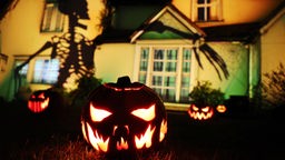 Ein Halloween typisch dekoriertes Haus. Im Vordergrund geschnitzte Kürbisse und dahinter der Schatten eines Skelett, projeziert auf eine Hauswand.