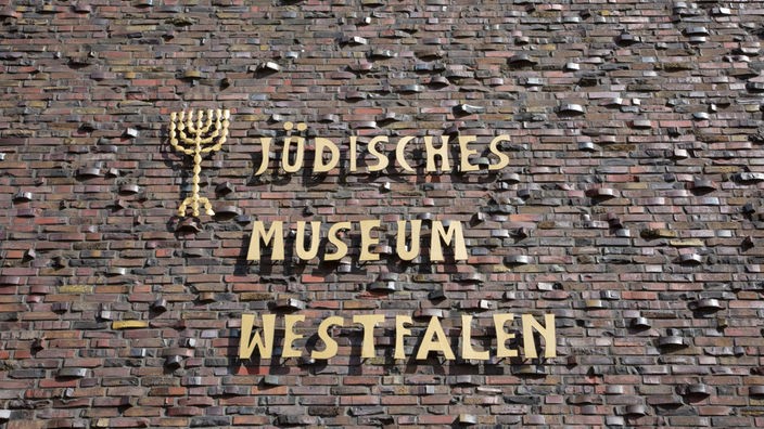 Die Fassade des Jüdische Museum Westfalen in Dorsten mit dem gleichnamigen, goldenen Schriftzug mit dem Logo eines siebenarmigen Leuchters.