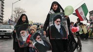 Eine Frau und ihre Kinder halten Bilder von Ajatollah Ruhollah Chomeini, dem ersten obersten Führer und Revolutionsführer, und dem aktuellen obersten Führer des Irans, Ajatollah Ali Chamenei.