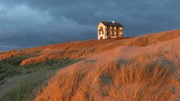 Ein einzelnes Haus auf der Düne im Abendlicht der holländischen Nordseeküste.
