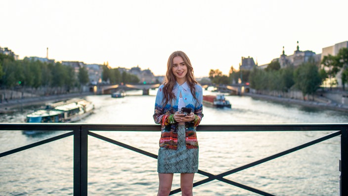 Schauspielerin Lily Collins steht beim Dreh der Netflix-Serie "Emily in Paris" auf einer Brücke in Paris.