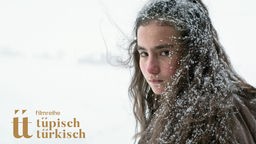 Plakat der Filmreihe "Tüpisch Türkisch" mit Filmstill aus "Auf trockenen Gräsern", das ein Mädchen mit Schneeflocken in den Haaren zeigt.