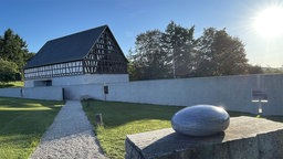 Außenansicht des Steinskultupturenmuseums der Fondation Kubach Wilmsem, Vorgrdun ein rund geschliffenes Stein-Objekt.