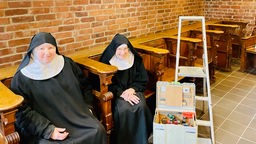 Zwei Benediktinerinnen aus der Klostergemeinschaft in Köln-Raderberg sitzen nebeneinander.