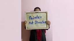 Eine anoyme afghanische Künsterlin verdeckt ihr Gesicht mit einer Leinwand, auf der "Painter" steht