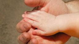 Das Beitragsbild des WDR3 Kulturfeature "Bindungslos" zeigt die Hände von Vater und Sohn. 