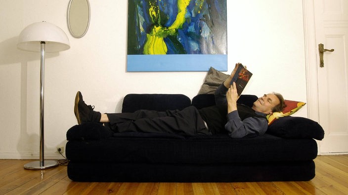 Das Beitragsbild des WDR3 Kulturfeature "Zwischen Musik und Politik" zeigt den Schriftsteller Peter Schneider auf einem Sofa liegend in seiner Wohnung in Berlin, 2005.