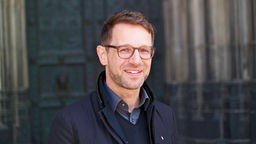 Der Kölner Dombaumeister Peter Füssenich lächelnd vor dem Dom