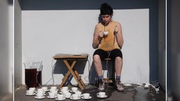 Performance "A Cup of Tea" von Cristiana Cott: Die Künstlerin spuckt Tee in Tassen.