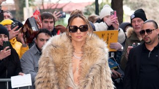 Jennifer Lopez mit Pelz und Sonnenbrille umringt von Fotografen und Fans.