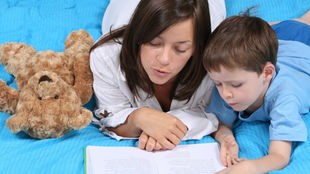 Eine junge Frau liest mit einem Kind.