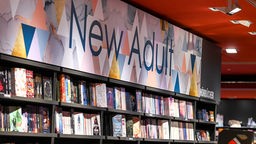 Symbolbild: Ein Bücherregal in einer Buchhandlung mit großem Schild mit der Aufschrift "New Adult".