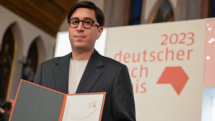 Der österreichische Autor Tonio Schachinger hält nach der Auszeichnung mit dem Deutschen Buchpreis 2023 für seinen Roman „Endzeitalter“ die Urkunde.