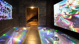 Installation "Inflorescences" von Sabrina Ratté: Lichtflächen und Projektionen in psychodelischen Farben und Formen an Wänden einer Werkshalle.
