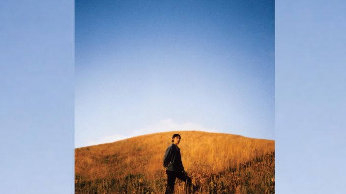 Das Albumcover zeigt Sam Burton bei blauem Himmel in einem Feld stehen.