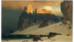 Das Gemälde "Das Gestade der Vergessenheit" von Eugen Bracht zeigt eine felsige Küste, der Felsspitzen in Sonnenlicht getaucht sind.