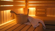 Ein Holzbottich und Handtücher in einer Sauna.