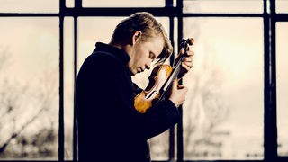 Ein Foto von Pekka Kuusisto mit seiner Geige. 