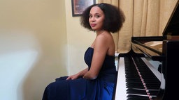 Pianistin Rebeca Omordia sitzt auf dem Pianohocker mit dem Rücken zugewandt der Klaviatur eines Flügels.