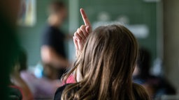 Schülerinnen und Schüler einer vierten Klasse einer Grundschule nehmen am Unterricht teil, eine Schülerin meldet sich