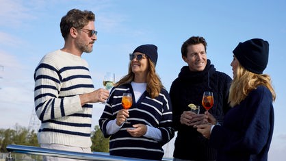 Vier Freunde stoßen an Bord mit Wein und Cocktails an