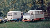 Zwei selbstgebaute Wohnmobile auf Campingplatz im Wald (1974)