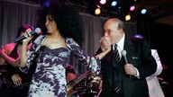 Clive Davis küsst Diana Ross die Hand auf der Bühne