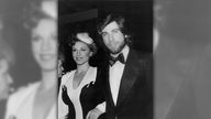 Schwarz-weiß Bild von John Travolta in Anzug und Fliege zusammen mit Marilu Henner bei der Verleihung des Golden Globes 1979.